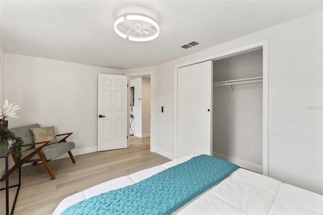 bedroom featuring light wood finished floors, baseboards, visible vents, and a closet