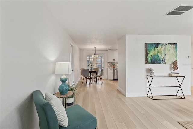 sitting room featuring baseboards, visible vents, and light wood finished floors