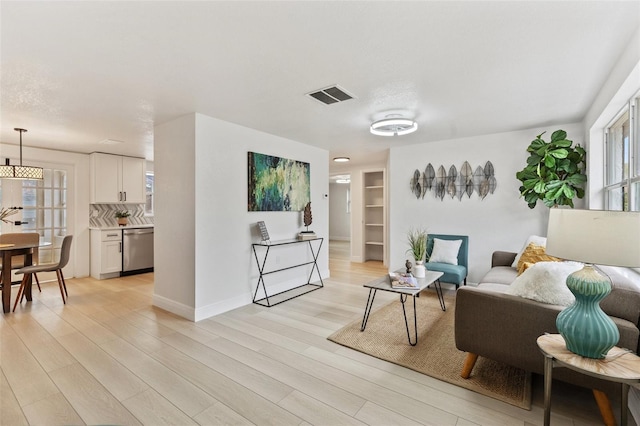 living area featuring light wood finished floors, baseboards, and visible vents