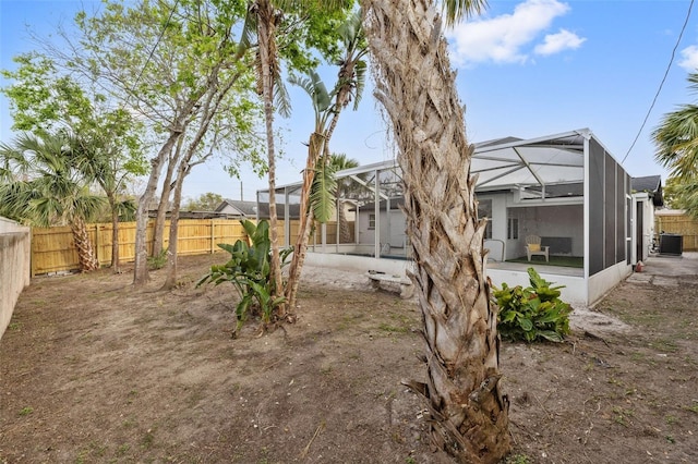 view of yard with glass enclosure, central AC unit, and a fenced backyard