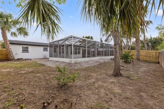 back of house with glass enclosure and a fenced backyard