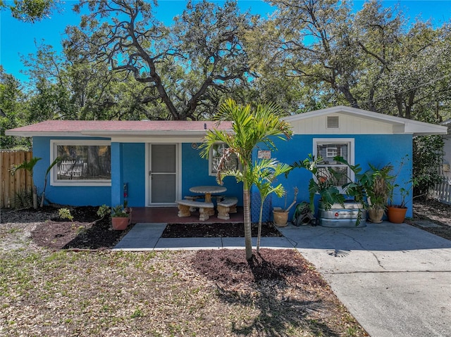 view of front of house featuring concrete driveway, fence, and stucco siding