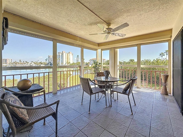 sunroom with a view of city, a water view, and a ceiling fan