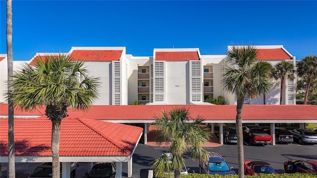 view of building exterior featuring covered and uncovered parking