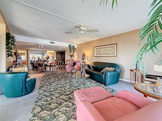 tiled living area featuring visible vents, ceiling fan, a textured ceiling, and baseboards