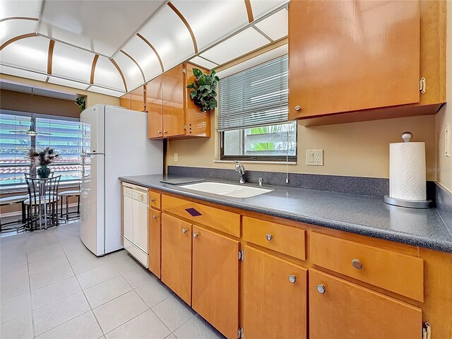 kitchen featuring dark countertops, white appliances, a sink, and light tile patterned floors