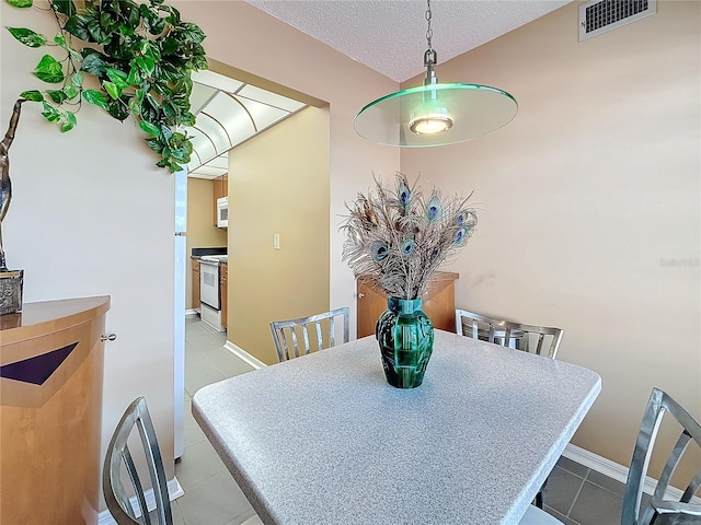 dining area with baseboards, visible vents, a textured ceiling, and light tile patterned flooring