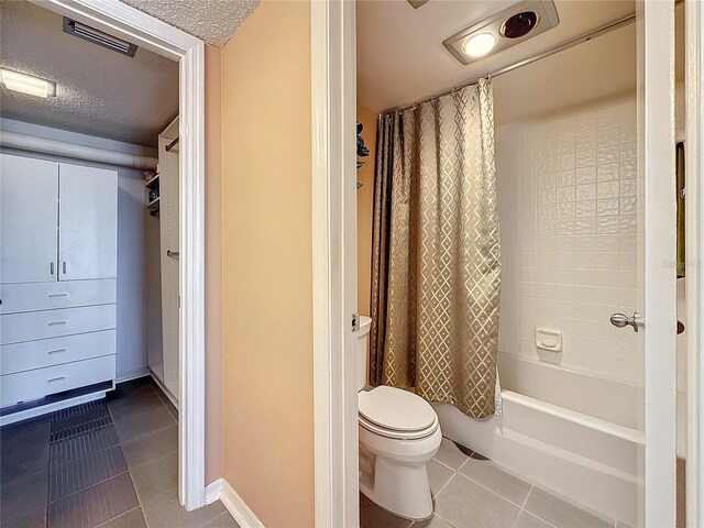 full bathroom with a textured ceiling, toilet, shower / tub combo, visible vents, and tile patterned floors