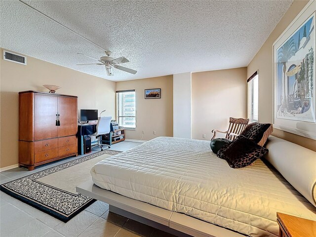 bedroom featuring baseboards, a textured ceiling, visible vents, and a ceiling fan