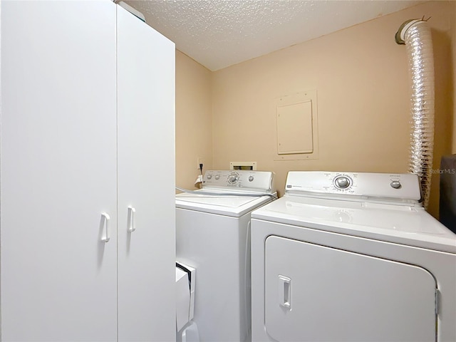 laundry room featuring a textured ceiling, washing machine and dryer, and cabinet space