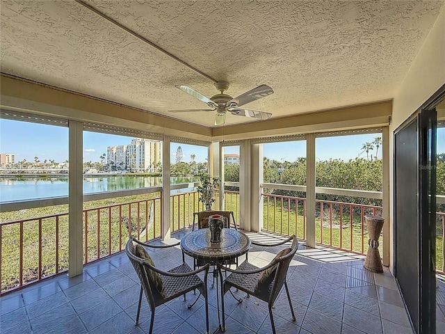 sunroom featuring a water view and ceiling fan