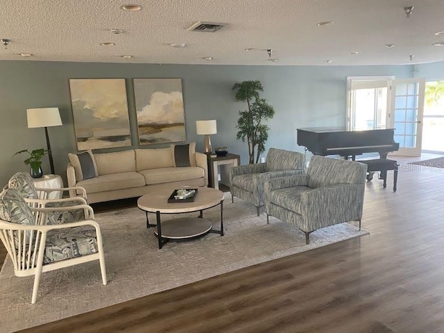 living area featuring visible vents, a textured ceiling, and wood finished floors