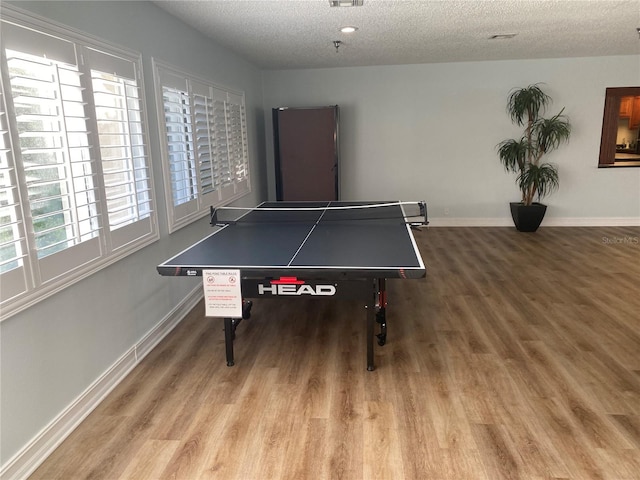 recreation room with visible vents, a textured ceiling, baseboards, and wood finished floors