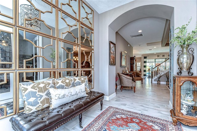 interior space with baseboards, visible vents, arched walkways, stairway, and wood finished floors