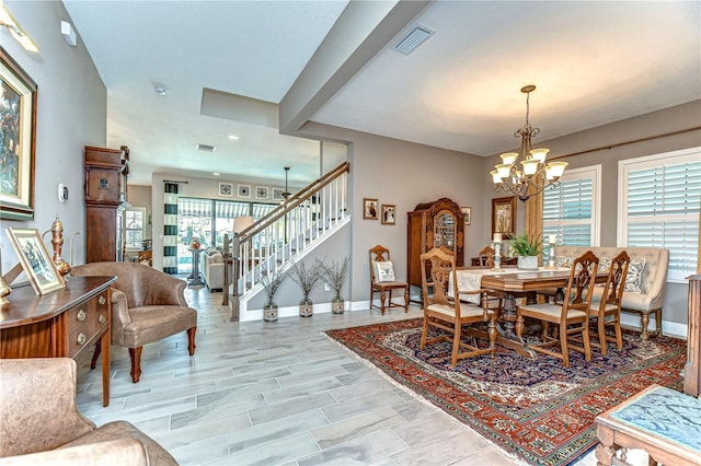 dining room with plenty of natural light, stairs, visible vents, and a chandelier