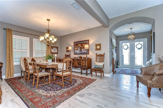 dining space with arched walkways, a healthy amount of sunlight, visible vents, and a notable chandelier