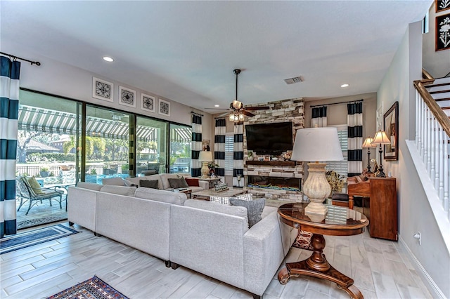 living area with recessed lighting, visible vents, a stone fireplace, wood finished floors, and stairs