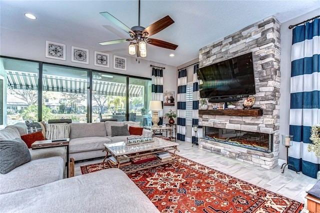 living room with ceiling fan and a stone fireplace