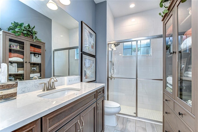 bathroom featuring a stall shower, vanity, and toilet