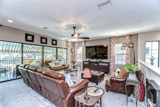 carpeted living area with plenty of natural light, visible vents, and a ceiling fan