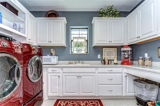 laundry area with light tile patterned floors, separate washer and dryer, a sink, and cabinet space