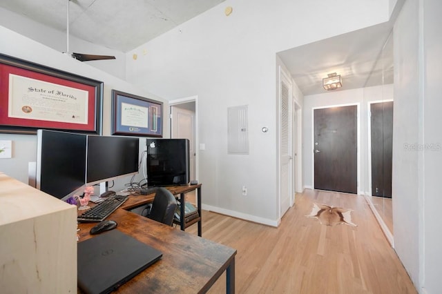 office area with light wood-type flooring, electric panel, and baseboards