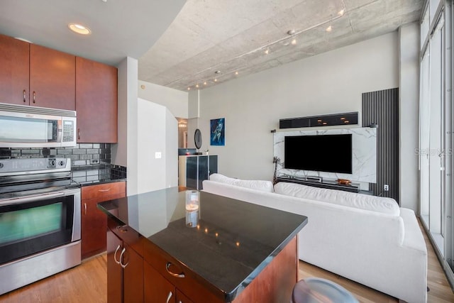 kitchen with stainless steel appliances, dark countertops, light wood-style flooring, decorative backsplash, and open floor plan