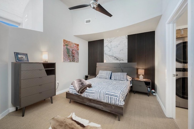 bedroom with carpet floors, visible vents, stacked washer / dryer, ceiling fan, and baseboards