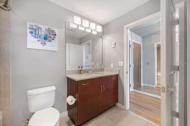 bathroom featuring toilet, tile patterned floors, baseboards, and vanity