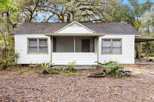 view of front of house featuring a carport, roof with shingles, and a sunroom