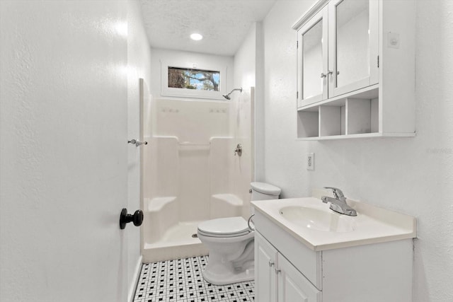 bathroom with a textured wall, toilet, a textured ceiling, a shower stall, and vanity