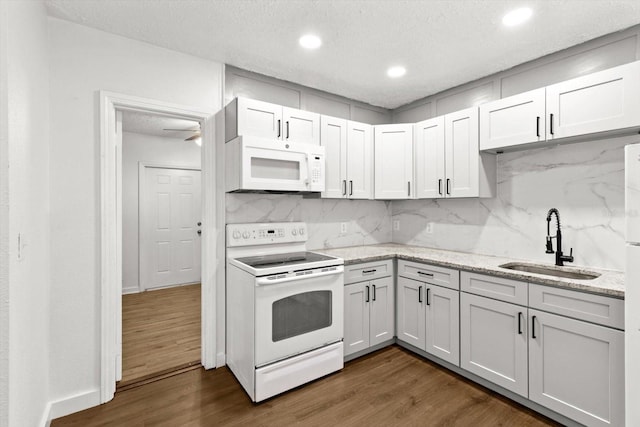 kitchen with dark wood-style floors, white appliances, a sink, and backsplash