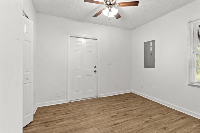 spare room with a textured ceiling, ceiling fan, wood finished floors, and electric panel