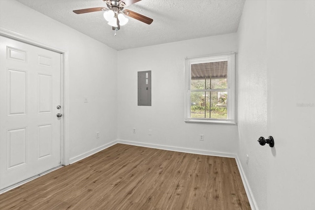 unfurnished room with electric panel, baseboards, a textured ceiling, and wood finished floors