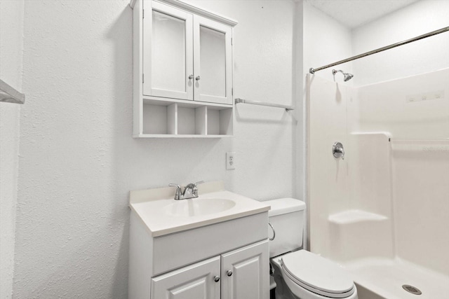 full bath with toilet, a textured wall, walk in shower, and vanity