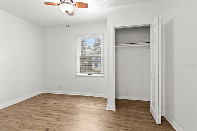 unfurnished bedroom with a textured ceiling, baseboards, and wood finished floors