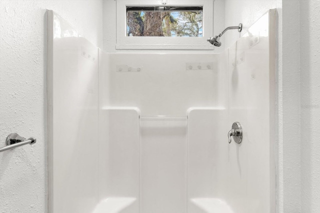 bathroom with a shower and a textured wall