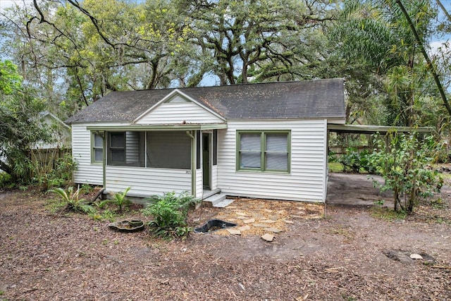 single story home featuring dirt driveway, fence, and roof with shingles