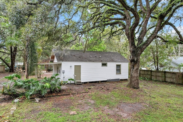 rear view of property with roof with shingles and fence