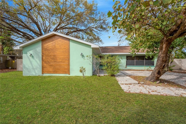 exterior space featuring stucco siding, fence, and a front yard