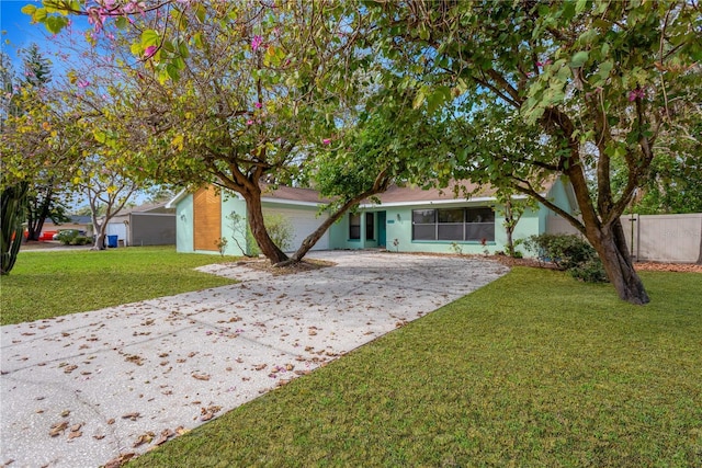 view of front facade with driveway, an attached garage, fence, and a front lawn