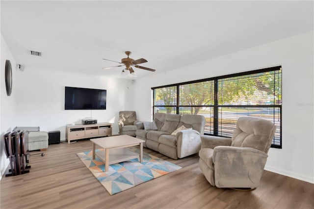 living room featuring baseboards, visible vents, ceiling fan, and wood finished floors