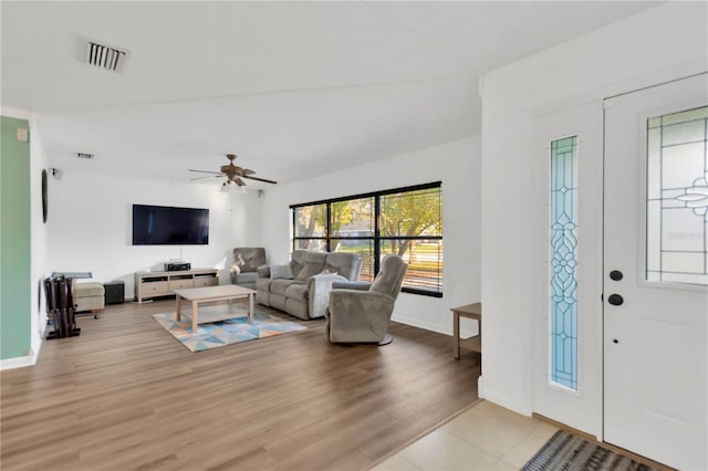 living room featuring light wood-type flooring, baseboards, visible vents, and a ceiling fan