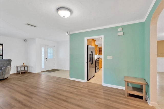 interior space with arched walkways, visible vents, light wood-style floors, ornamental molding, and baseboards