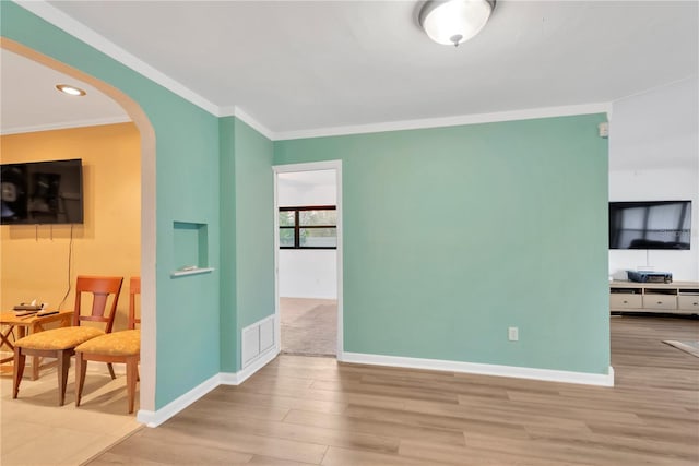 living area featuring arched walkways, baseboards, wood finished floors, and crown molding