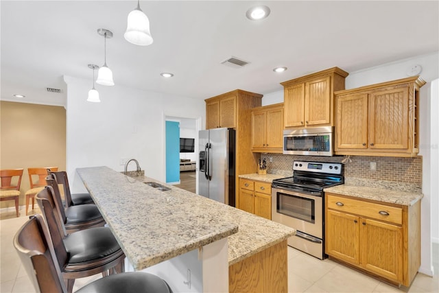 kitchen with appliances with stainless steel finishes, visible vents, a sink, and tasteful backsplash