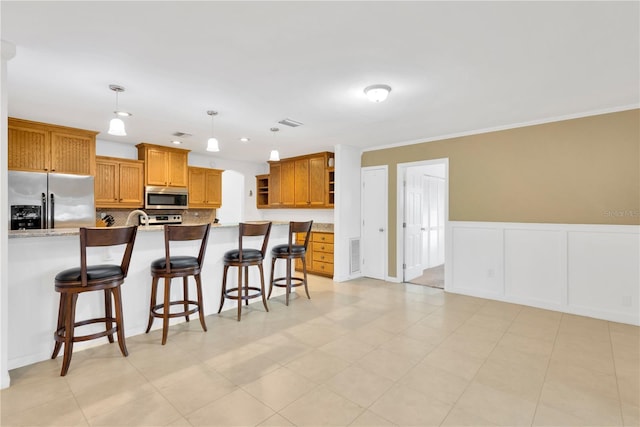 kitchen featuring appliances with stainless steel finishes, brown cabinets, a breakfast bar area, and open shelves