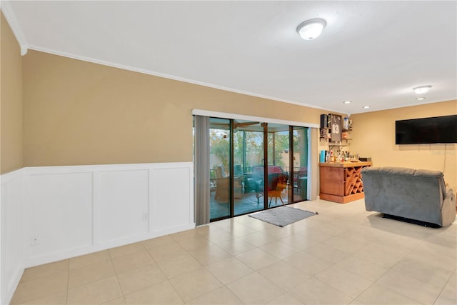 living area featuring a wainscoted wall, ornamental molding, and a decorative wall