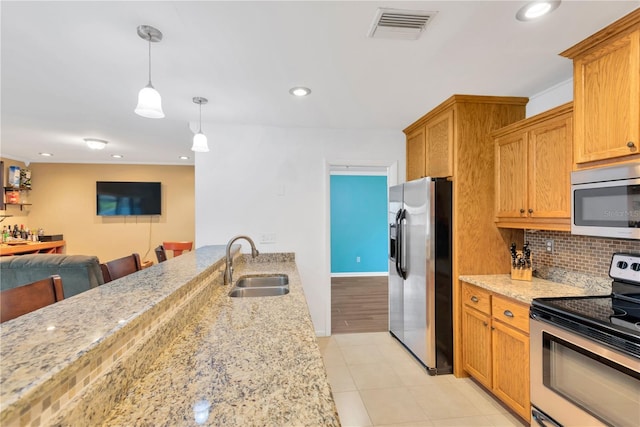 kitchen with a sink, visible vents, open floor plan, appliances with stainless steel finishes, and decorative backsplash