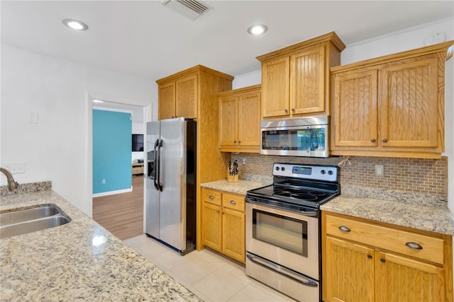 kitchen featuring light tile patterned floors, visible vents, decorative backsplash, stainless steel appliances, and a sink